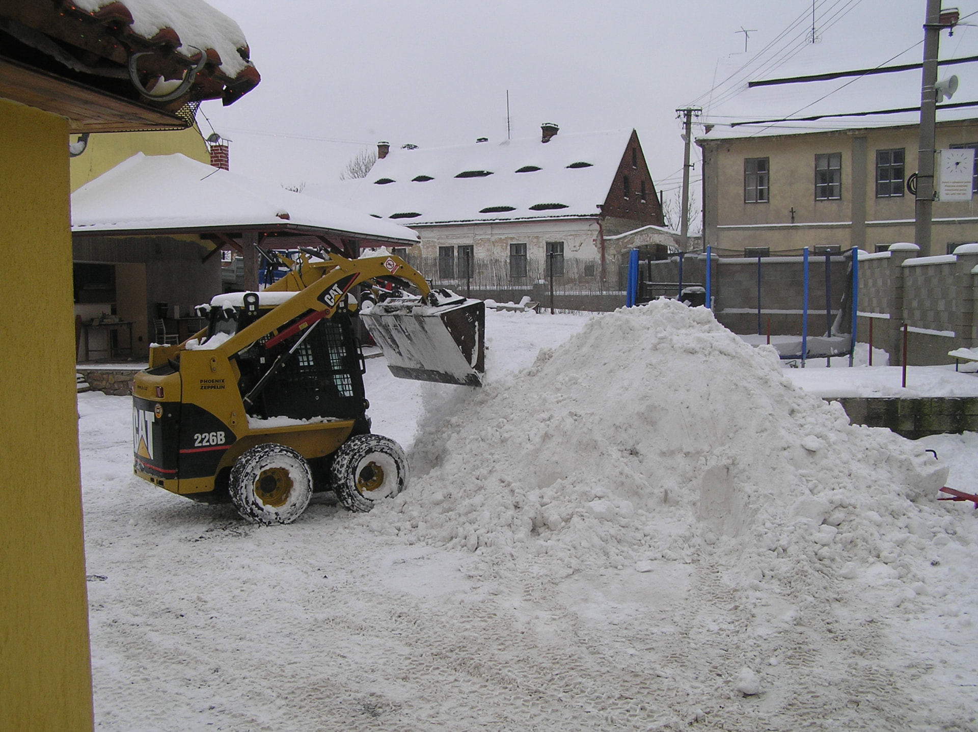 Nakladač CAT 226B odklízí sníh na dvoře
