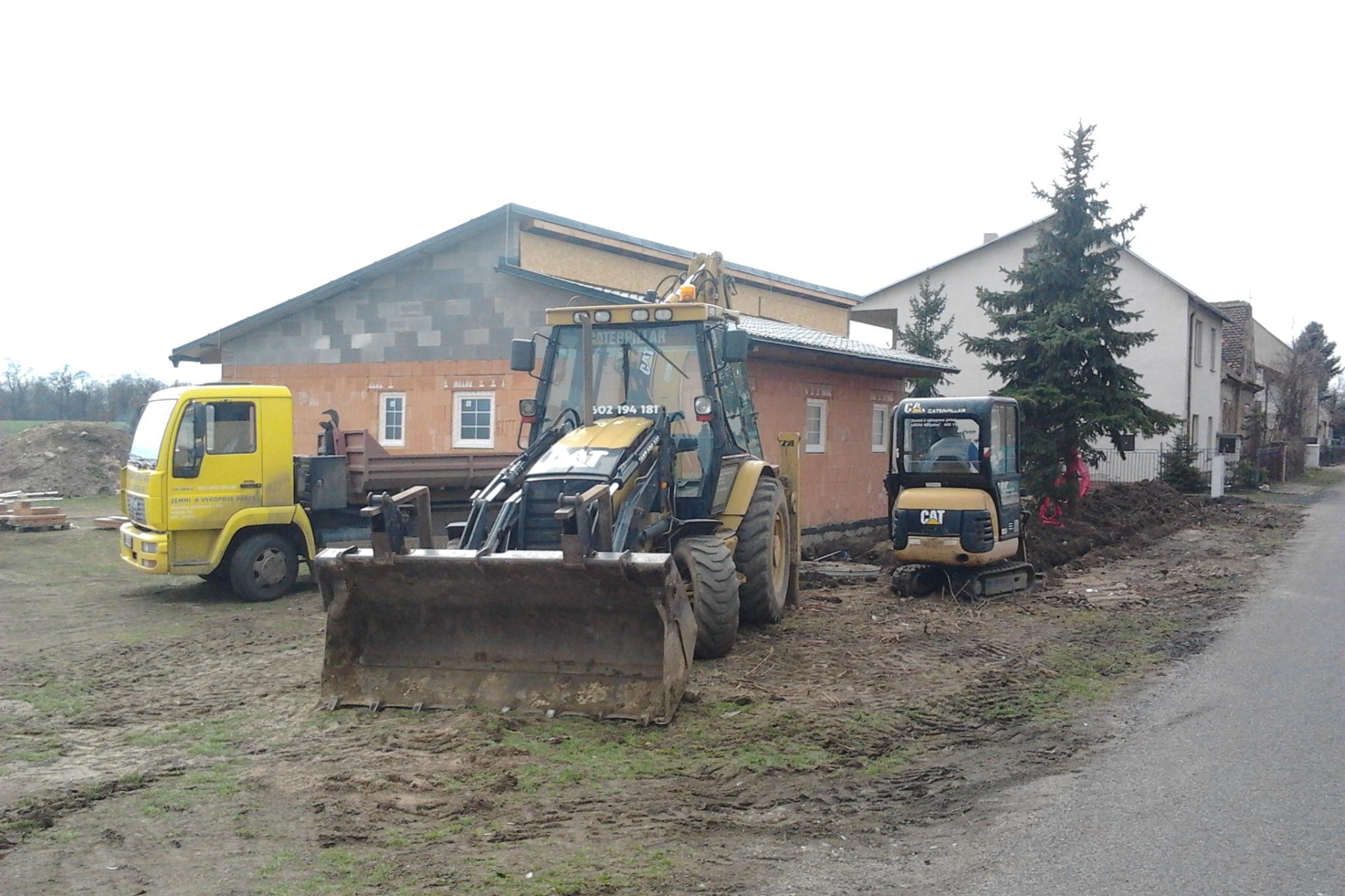 Traktorbagr, minirypadlo a nákladní vůz na jedné stavbě